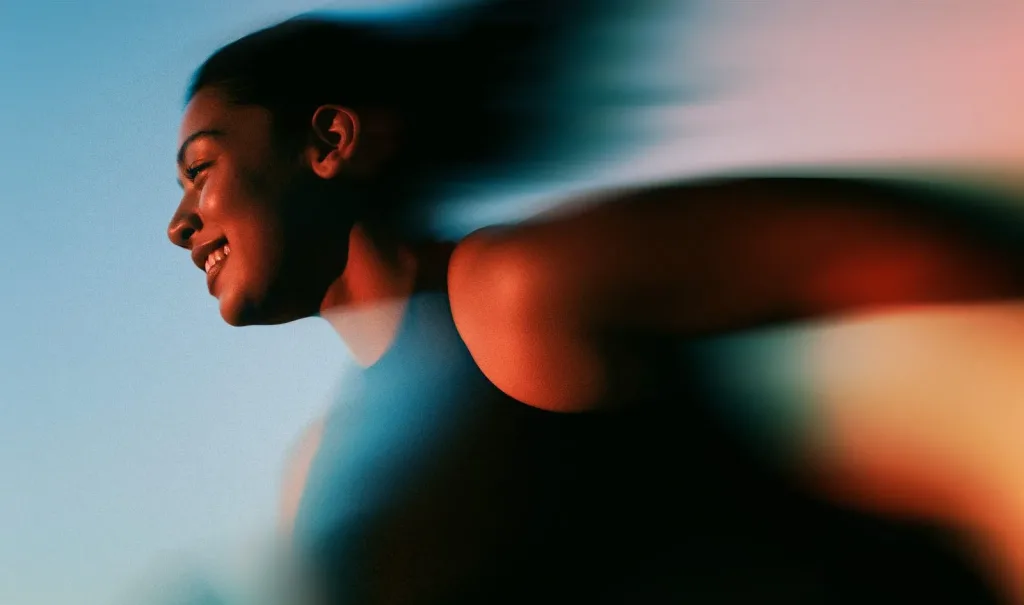 Woman smiling mid-stride, blurred with movement